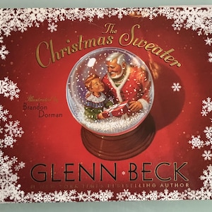 May include: A hardcover book titled "The Christmas Sweater" by Glenn Beck. The cover features a snow globe with Santa Claus and a child, set against a red background with snowflake accents. The author's name is prominently displayed.