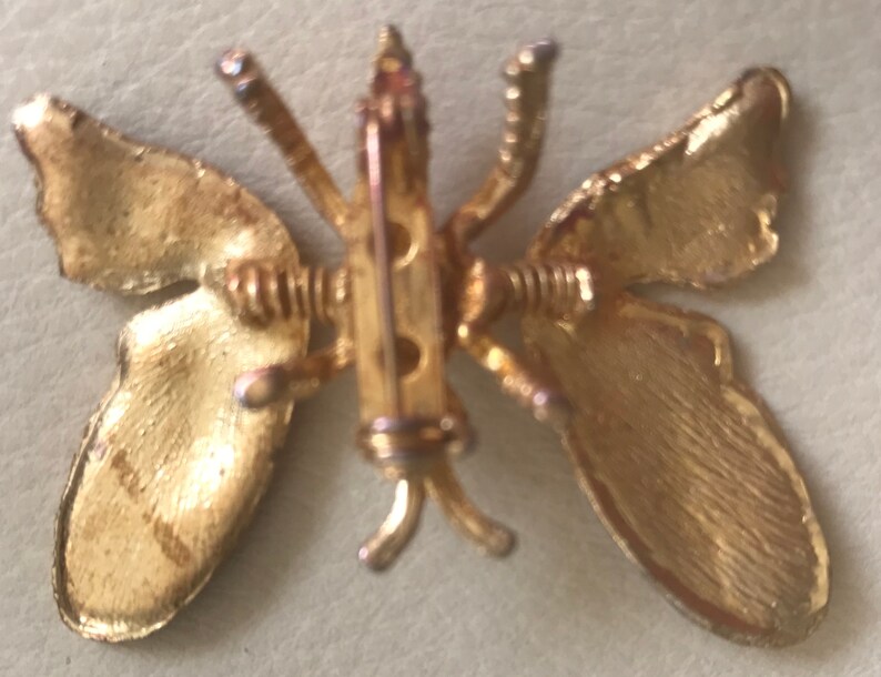 Puede incluir: Broche de mariposa dorada con un dise&ntilde;o detallado. Las alas son texturizadas y la broche tiene un cierre de pin.