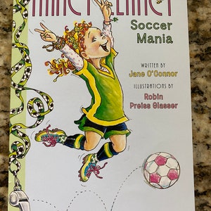 May include: A book cover featuring a cartoon girl with red hair kicking a soccer ball. The book title is "Nancy Clancy Soccer Mania" and the author is Jane O'Connor. The book is part of a series and is book number 6.