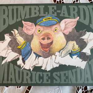 May include: A green book cover with the title "Bumble-Ardy" in white lettering. A cartoon pig wearing a blue cap is peeking out from a torn hole in the cover. The author's name, "Maurice Sendak", is printed in white lettering below the pig.