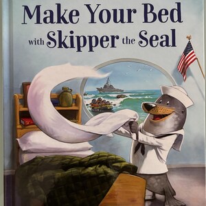 May include: A children's book cover featuring a cartoon seal wearing a sailor hat and making a bed. The book title is "Make Your Bed with Skipper the Seal" and the author is Admiral William H. McRaven (Ret.).