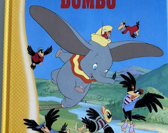 May include: A blue book with a yellow spine features a Disney illustration of Dumbo the elephant flying with a group of crows. The book title is "Dumbo" in red letters.