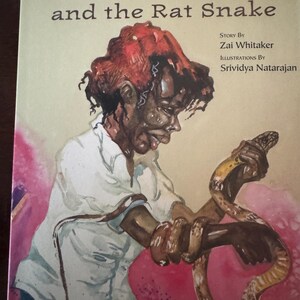 May include: A book cover with an illustration of a young person holding a snake. The book title is "KALI and the Rat Snake". The text "Story By Zai Whitaker" and "Illustrations By Srividya Natarajan" are also on the cover.