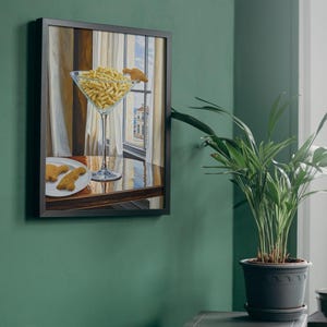 May include: A framed painting of a martini glass filled with crackers and a plate with two crackers on a wooden table. The painting is hanging on a green wall.