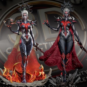 Puede incluir: Dos estatuas detalladas de una figura femenina con piel pálida, cabello blanco y detalles rojos. Las figuras visten trajes grises oscuros y negros con capas rojas. Una se alza sobre una base de llamas, la otra sobre una base oscura y puntiaguda. Ambas sostienen armas.