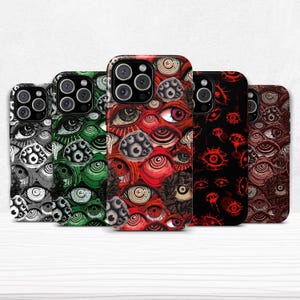 Puede incluir: Cinco fundas para teléfono con diseños de ojos en varios colores. Los diseños incluyen blanco y negro, verde, rojo y marrón. Cada funda muestra una disposición diferente de ojos, ofreciendo una apariencia llamativa y artística.