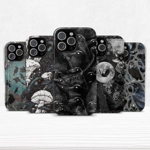 May include: A collection of five phone cases with dark, gothic-themed designs. The cases feature illustrations of crows, mushrooms, and floral elements in shades of black, gray, and white. The designs vary, with some showcasing a full moon and others a flock of crows.