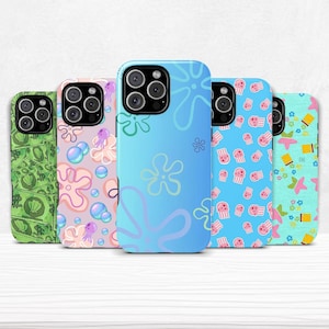 May include: A collection of five phone cases with colorful designs. The cases feature various patterns, including money, bubbles, flowers, jellyfish, and starfish. The cases are designed to fit a smartphone and have a camera cutout.