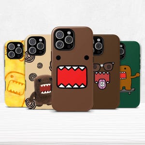 Puede incluir: Cinco fundas para teléfono con diseños de Domo-kun en varios colores. Las fundas muestran la cara y la boca de Domo-kun, con una funda con gafas y otra en monopatín. Los colores incluyen amarillo, beige y marrón. Para un teléfono móvil.