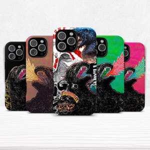 May include: A collection of phone cases featuring Godzilla illustrations. Each case showcases a different design, with Godzilla roaring and emitting colorful energy blasts. The cases have a glossy finish and are designed to fit various phone models.