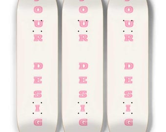 May include: Three white skateboards with pink text that reads "YOUR DESIGN". The skateboards have a rounded top and bottom. The text is vertically aligned down the center of the board.