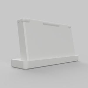 Op de afbeelding: Een witte, schuine displaystandaard met een rechthoekige basis en een achterpaneel. De standaard heeft een kleine, afgeronde handgreep aan de bovenkant en is ontworpen om een tablet of ander apparaat vast te houden. De standaard is gemaakt van een solide, ondoorzichtig materiaal.