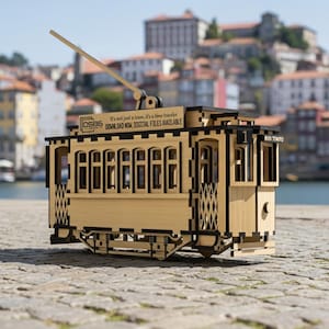 Puede incluir: Maqueta de madera de un tranvía antiguo con detalles recortados y acentos negros. El tranvía tiene un brazo levantado y el texto "RIO TINTO" en el lateral. También se ve el texto "It's not just a tram, it's a time traveler".