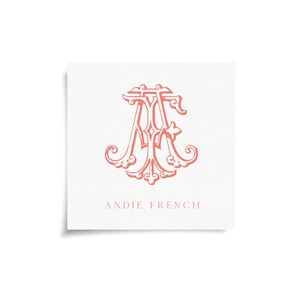 May include: A square card with a coral-colored monogram design featuring the letters A and F intertwined with decorative flourishes. The words "ANDIE FRENCH" are printed below the monogram in a matching coral hue.