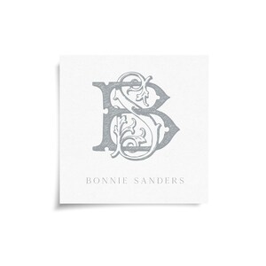 May include: A square card with a gray monogram design featuring the letters "B" and "S" intertwined with decorative flourishes. The name "Bonnie Sanders" is printed in a simple font below the monogram on a white background.