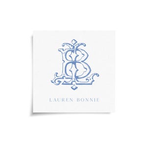 May include: A square card with a light blue monogram of the letters "LB" in an ornate, vintage style. The name "LAUREN BONNIE" is printed in a matching light blue font below the monogram. The background is white.