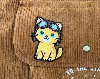 Parche bordado de gato naranja con casco de vuelo