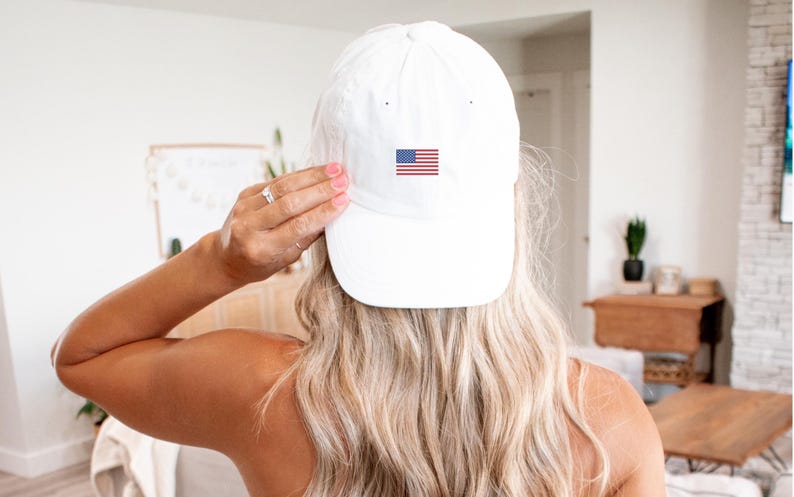 Puede incluir: Gorra de b&eacute;isbol blanca con visera curva. La gorra presenta una peque&ntilde;a bandera estadounidense bordada en la parte delantera. El sombrero est&aacute; hecho de un material suave y es un accesorio cl&aacute;sico e informal.
