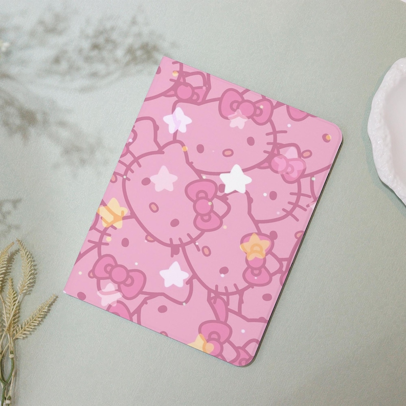 May include: Pink notebook cover with a repeating pattern of Hello Kitty characters and stars.