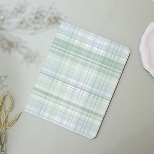 May include: A rectangular notebook with a plaid pattern in shades of green and blue. The notebook has rounded corners and a white background. The design is a classic plaid, with intersecting lines creating a grid-like pattern.