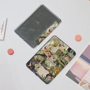 May include: A clear, rectangular phone case with a floral collage design. The collage includes images of flowers, houses, and text. A clear case and a pink circle are also visible.