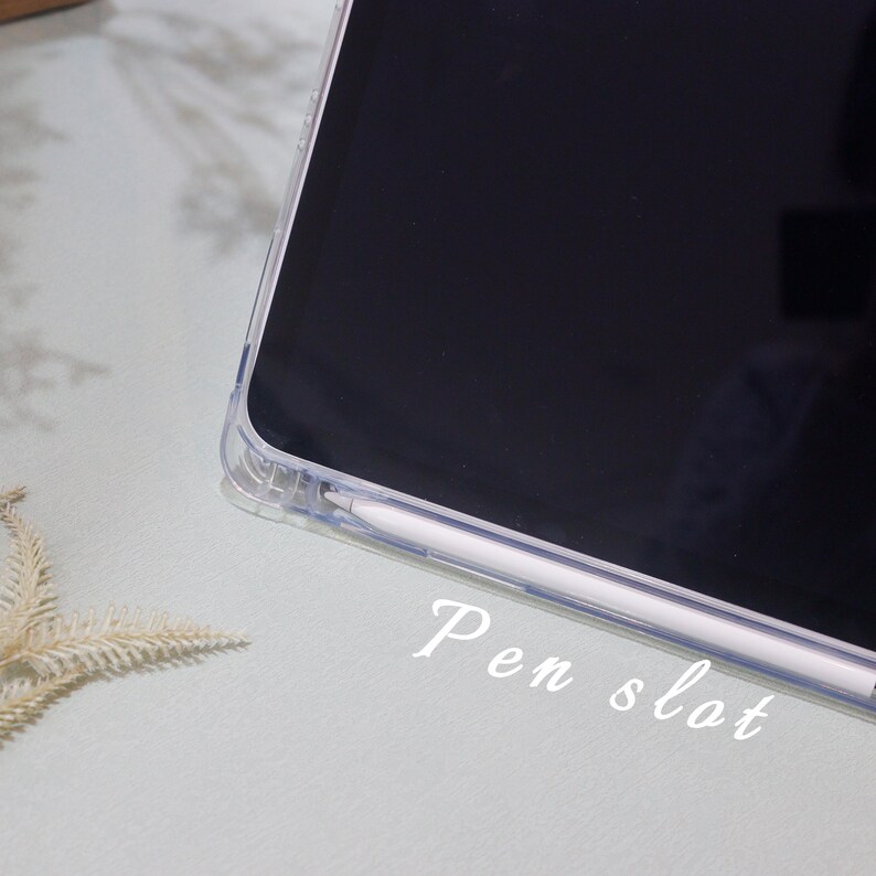 May include: A clear plastic case for a tablet with a slot for a stylus pen. The text "Pen slot" is written below the stylus.