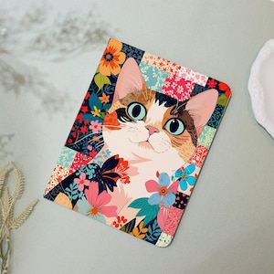 May include: A colorful cat illustration on a rectangular surface. The cat has big blue eyes, and a white, brown, and orange coat. The background is a patchwork of floral patterns in various colors, including pink, blue, and orange.