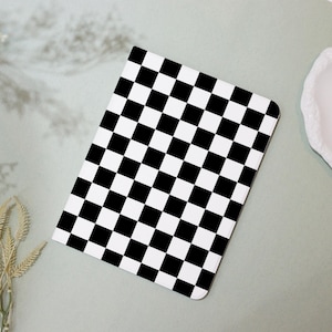 Może przedstawiać: Okładka notesu w czarno-białą kratkę. Okładka wykonana jest z trwałego materiału i ma elegancki, nowoczesny design.