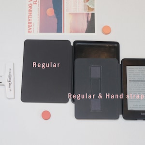 May include: A collection of dark gray e-reader covers, one labeled "Regular" and another "Regular & Hand strap." The e-reader is visible on the right. The background includes a magazine clipping and a small orange circle.