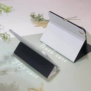 May include: Two tablet cases, one white and one black, are shown in different positions. The white case is folded into a stand position, with the text "Book case" written on the case. The black case is folded into a stand position, with the text "Flip case" written on the case.