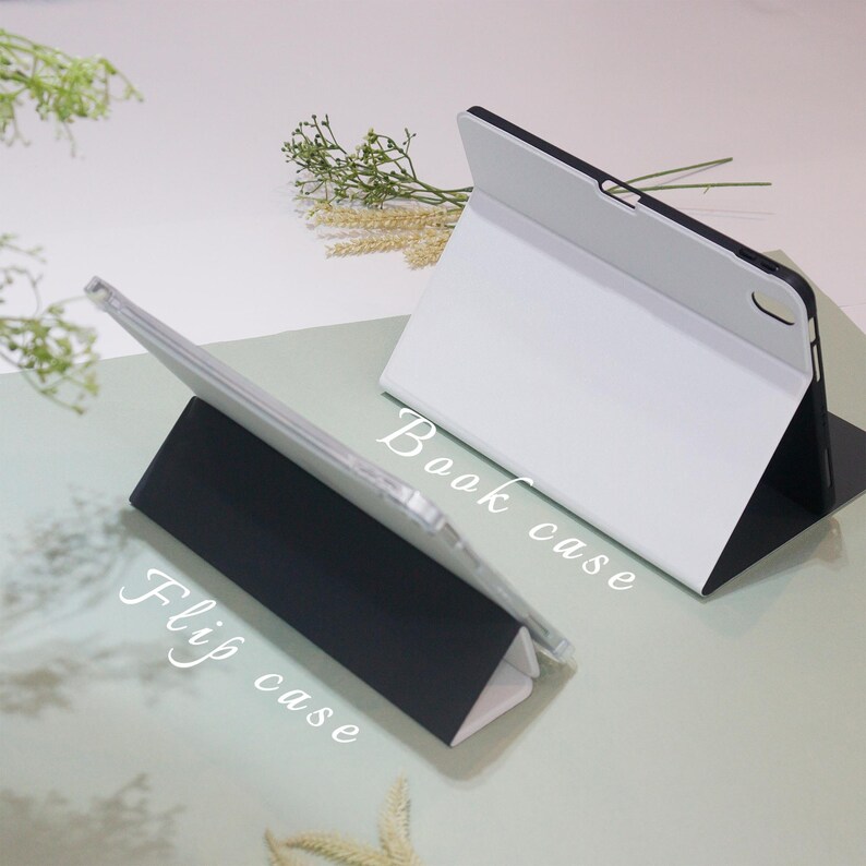 May include: Two tablet cases, one white and one black, are shown in different positions. The white case is folded into a stand position, with the text "Book case" written on the case. The black case is folded into a stand position, with the text "Flip case" written on the case.