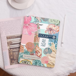 Könnte beinhalten: Ein Notizbuchcover im Collage-Stil mit blauem und grünem Hintergrund. Das Cover zeigt verschiedene Bilder, darunter Muscheln, ein Surfbrett, eine Qualle, eine Einsiedlerkrebs und eine Hibiskusblüte. Der Text "Ocean Blvd" und "Stay Wild, Ocean Child" ist ebenfalls auf dem Cover zu sehen.