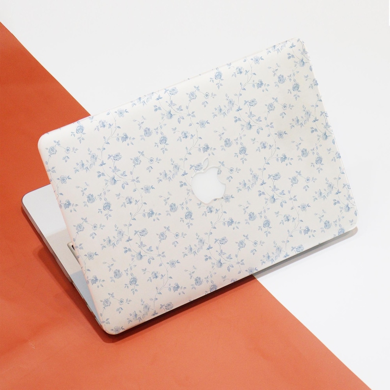 May include: A white laptop with a blue floral pattern on the lid. The Apple logo is visible on the lid.