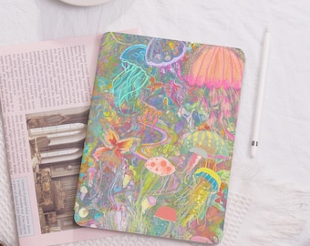 May include: A colorful tablet case featuring a vibrant, psychedelic design of jellyfish in shades of pink, yellow, blue, and green. The case is set against a white background with a newspaper and a white stylus.