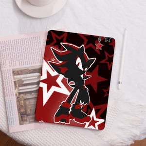 May include: A red and black iPad case featuring a silhouette of Shadow the Hedgehog from the Sonic the Hedgehog video game series. The case has a repeating pattern of white stars on a red background.