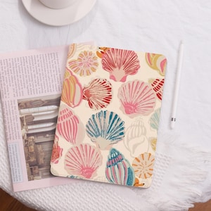 May include: A cream-colored notebook cover with a colorful seashell pattern. The shells are in shades of pink, red, blue, yellow, and orange. The cover has a matte finish.