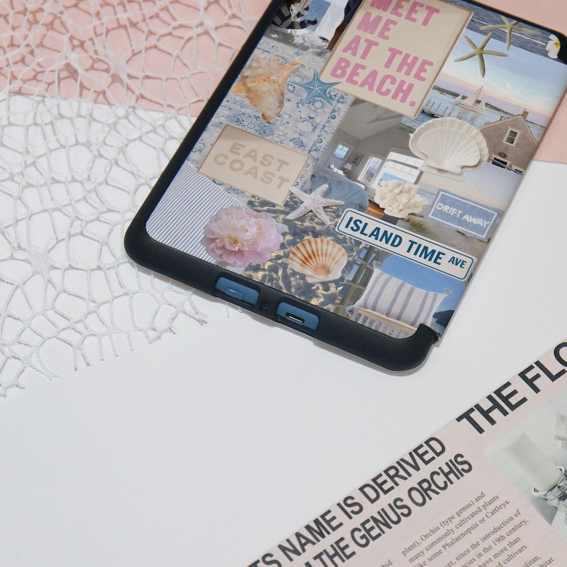 May include: A black e-reader with a collage of images on the screen. The images include a seashell, a starfish, a beach scene, and the text "Meet me at the beach." The e-reader is on a white surface.