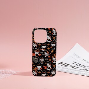 May include: Black phone case featuring a repeating pattern of cartoon cats in Halloween costumes, including witch hats and capes, with pumpkins and bats. The case has a cutout for the camera and buttons.