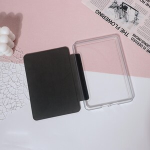 May include: A clear plastic case with a black cover for an e-reader. The case is open and the cover is lying next to it.