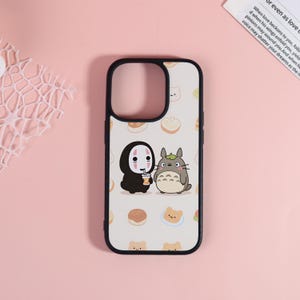 May include: A phone case with a black frame and a white backdrop, decorated with cartoon characters. The design includes a character in a black cloak and a grey, furry creature. The background has a pattern of small food illustrations.