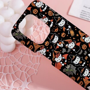 May include: Black phone case featuring a Halloween-themed pattern. The design includes cartoon cats in witch hats and capes, bats, and pumpkins. The case has a glossy finish and a cutout for the camera.