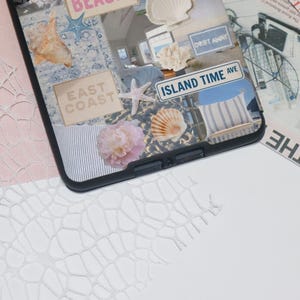 May include: A black phone case with a collage of images, including a seashell, a starfish, a flower, and text that says "East Coast", "Drift Away", and "Island Time Ave".