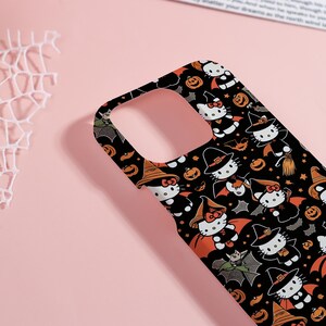 May include: Black phone case featuring a Halloween-themed pattern. The design includes cartoon characters dressed as witches and bats, along with pumpkins. The case has an orange and black color scheme.