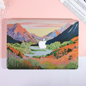 May include: Laptop case featuring a vibrant landscape painting of mountains, a lake, and colorful foliage. The design includes shades of orange, green, blue, and purple. A white Apple logo is centered on the case. The case is designed to fit a laptop.