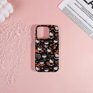 May include: Black phone case featuring a Halloween-themed pattern with cartoon characters, bats, pumpkins, and witch hats. The case has a glossy finish and is designed for a smartphone. The design is repeated across the surface.