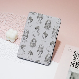 May include: A gray and white patterned e-reader cover with a repeating design of black and white illustrations of ancient Greek busts.