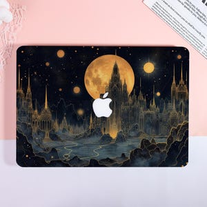 May include: A laptop skin featuring a dark night sky with a large golden moon, glowing stars, and a detailed gothic castle silhouette. The design includes a central white Apple logo cutout, with intricate golden line art depicting spires and rocky terrain.