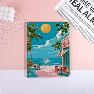 May include: A notebook featuring a beach scene with palm trees, a cafe, and a bright yellow sun. The notebook has a pink and blue color scheme, with the text "Vivaldi" on the cafe. The background is a light pink.