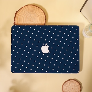 May include: A dark navy blue laptop skin featuring a repeating pattern of small white polka dots. The skin is applied to the lid of a laptop, leaving the silver Apple logo cutout visible in the center of the device's rectangular surface.