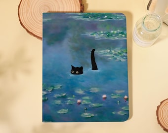 May include: A notebook featuring a whimsical illustration of a black cat in a pond, with only its head and tail visible above the water. The design is reminiscent of a Monet painting, with a blue and green color palette.